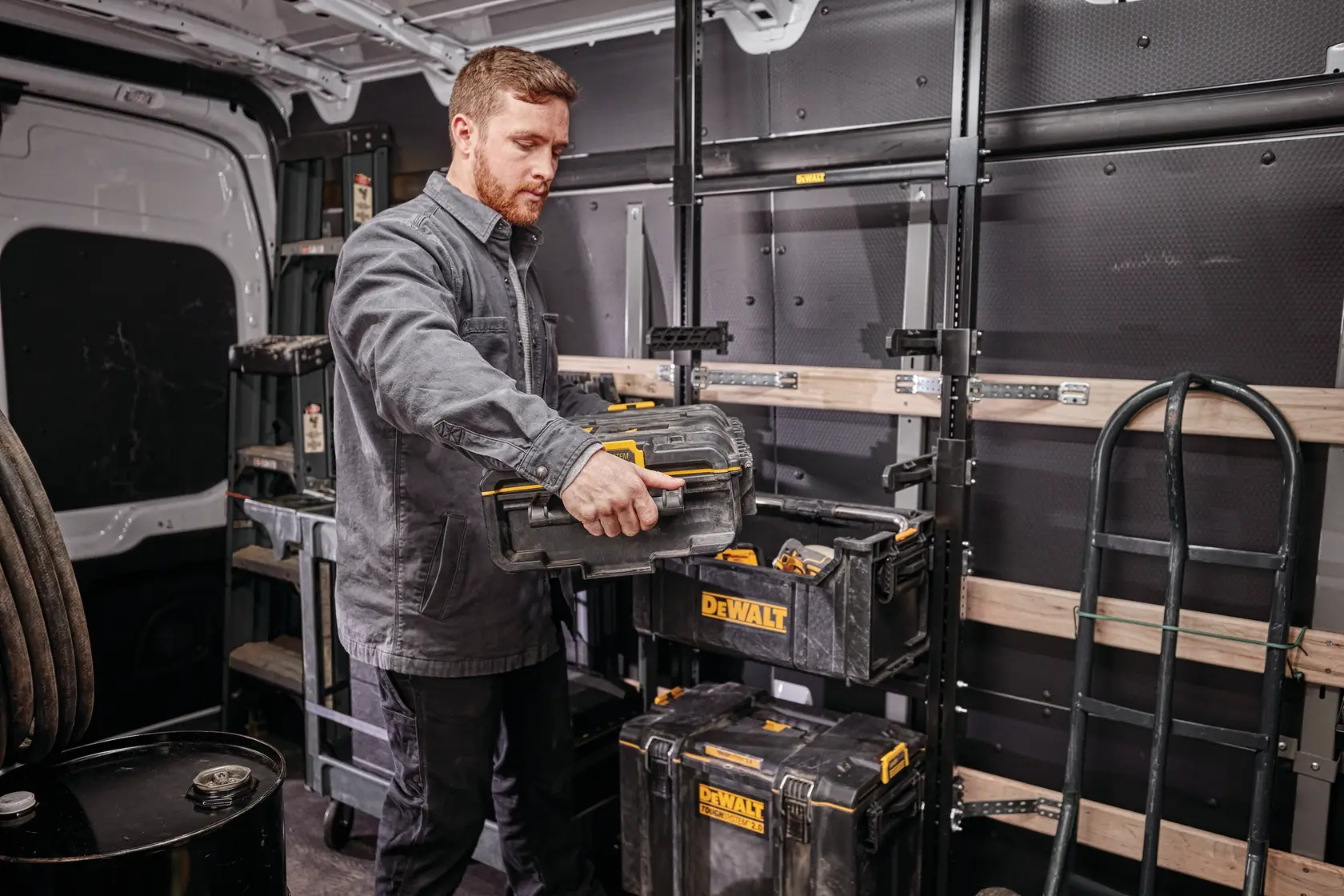 Person organizing DEWALT toolboxes in a van with racks and equipment.