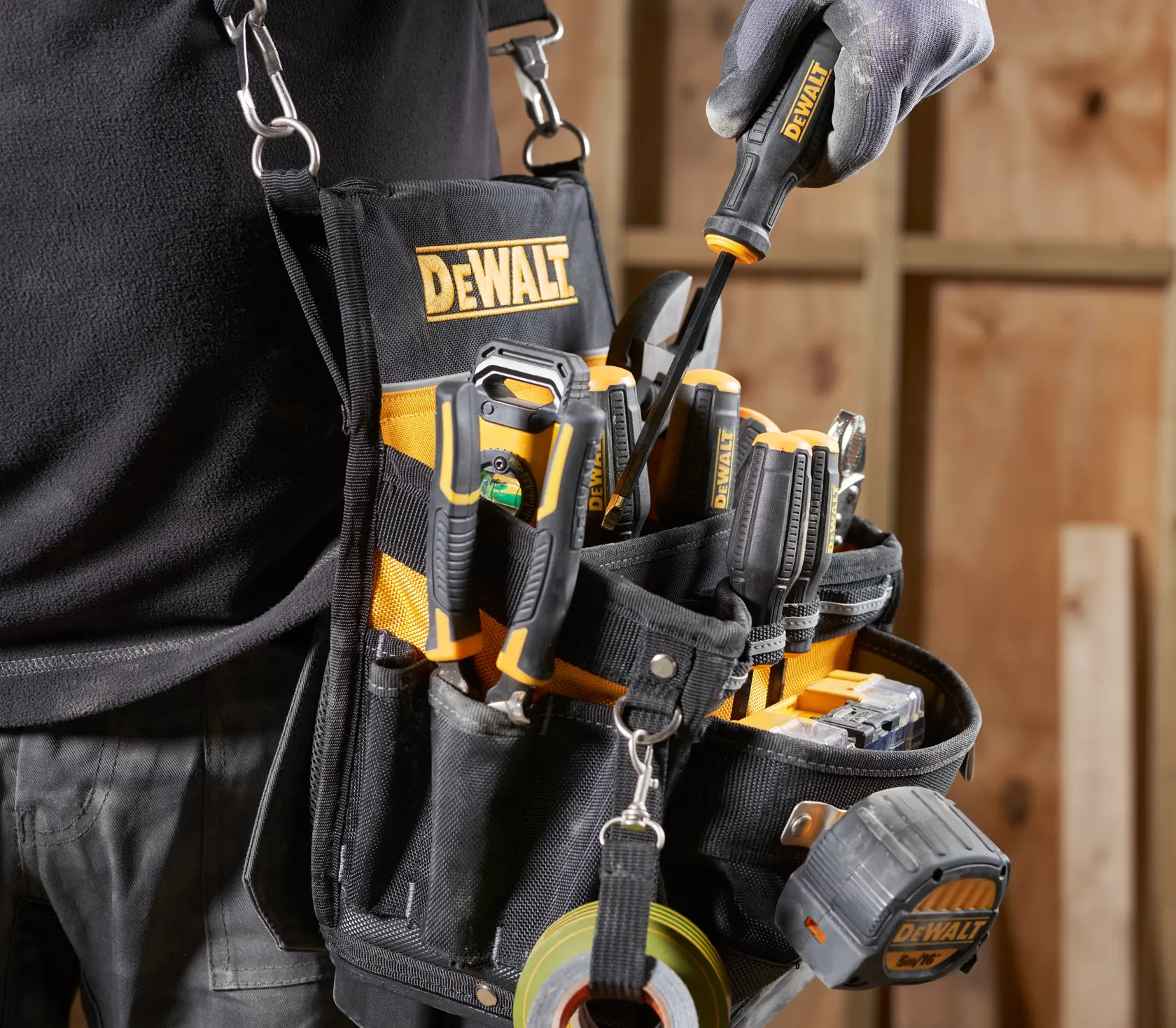 DEWALT tool belt with assorted tools and tape measure in carpenter's workshop.